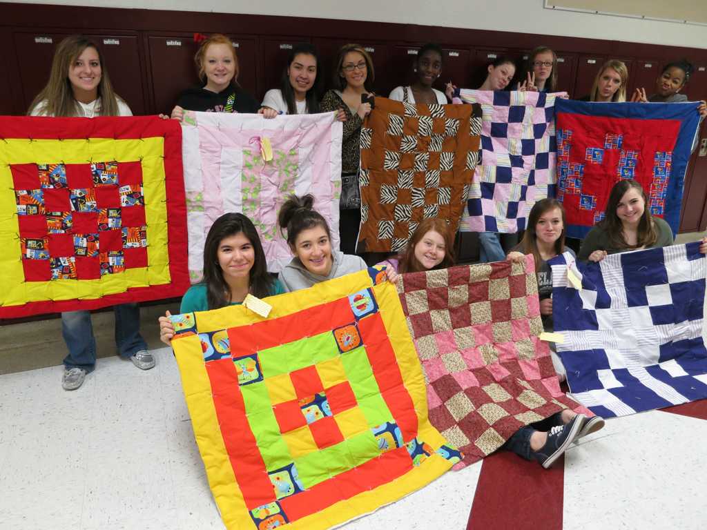 Students show off their quilts made for infants. 