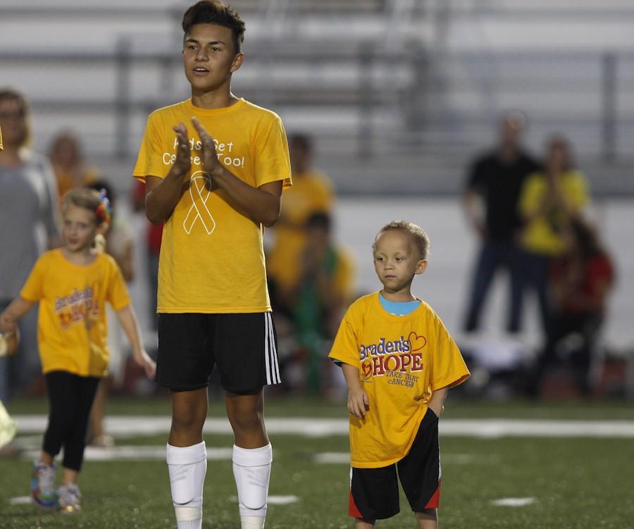 Oscar Aguilar claps for the cancer victims, as he stands with Dominick a young cancer victim
