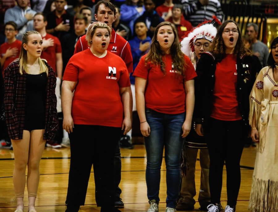 Alice Barnard (second to the left) sings the National Anthem with fellow choir members at the Winter Pep Assembly.