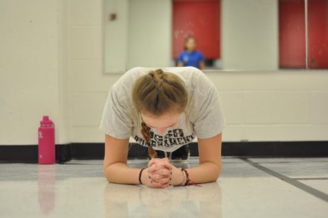 Fingers crossed and head down, sophomore Adie Basey does a 30 second plank. photo by Rilee Morrow