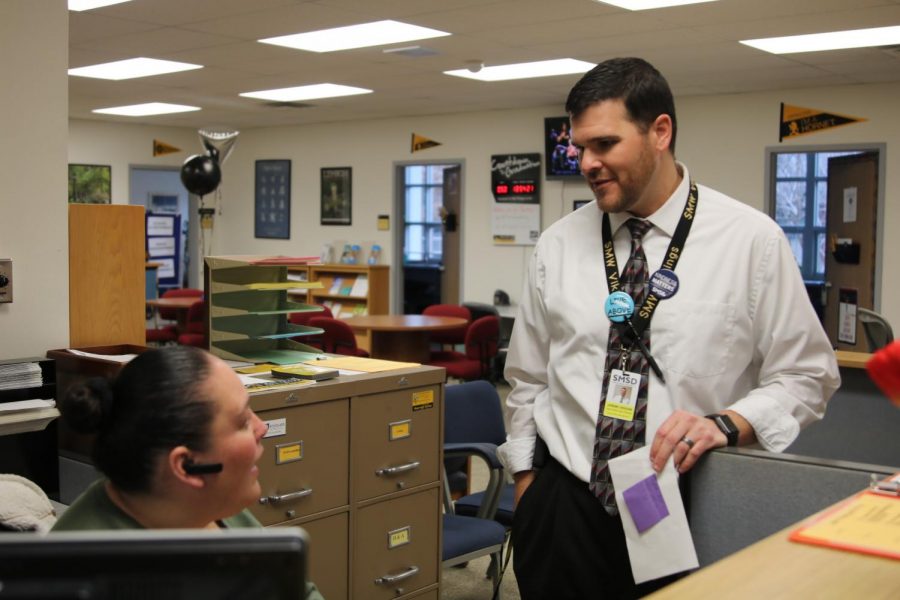Paper in hand, future SM North Principal Jeremy Higgins talks to SM West counseling office receptionist Alba Gonzales. photo by Caitlyn Braxdale