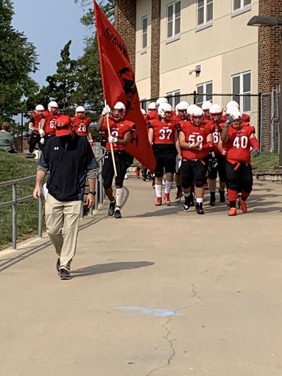 Coach Walter leads the football team to their first game of the season.