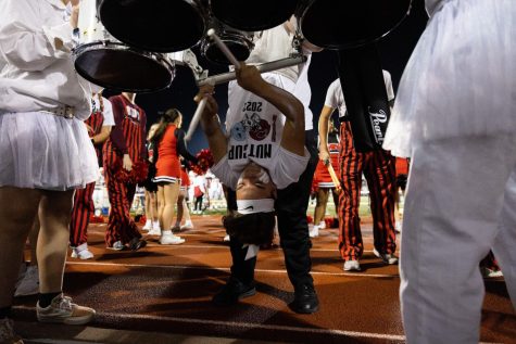 After the third quarter of the Nut Cup game on Sept. 23, junior drumline member Owen English plays the cadence “mary” upside down. Photo by Teryn Debey