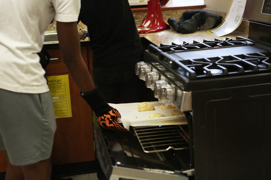 As the timer went off, freshman Jeran Barnett helps his foods group make cookies. Barnett was the first to get up to grab the teams cookies. I am safely removing cookies from the oven Barnett said. 